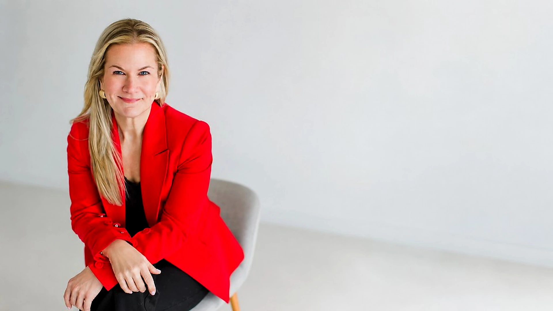 Marian Kalvert seated in a red blazer in a bright studio setting